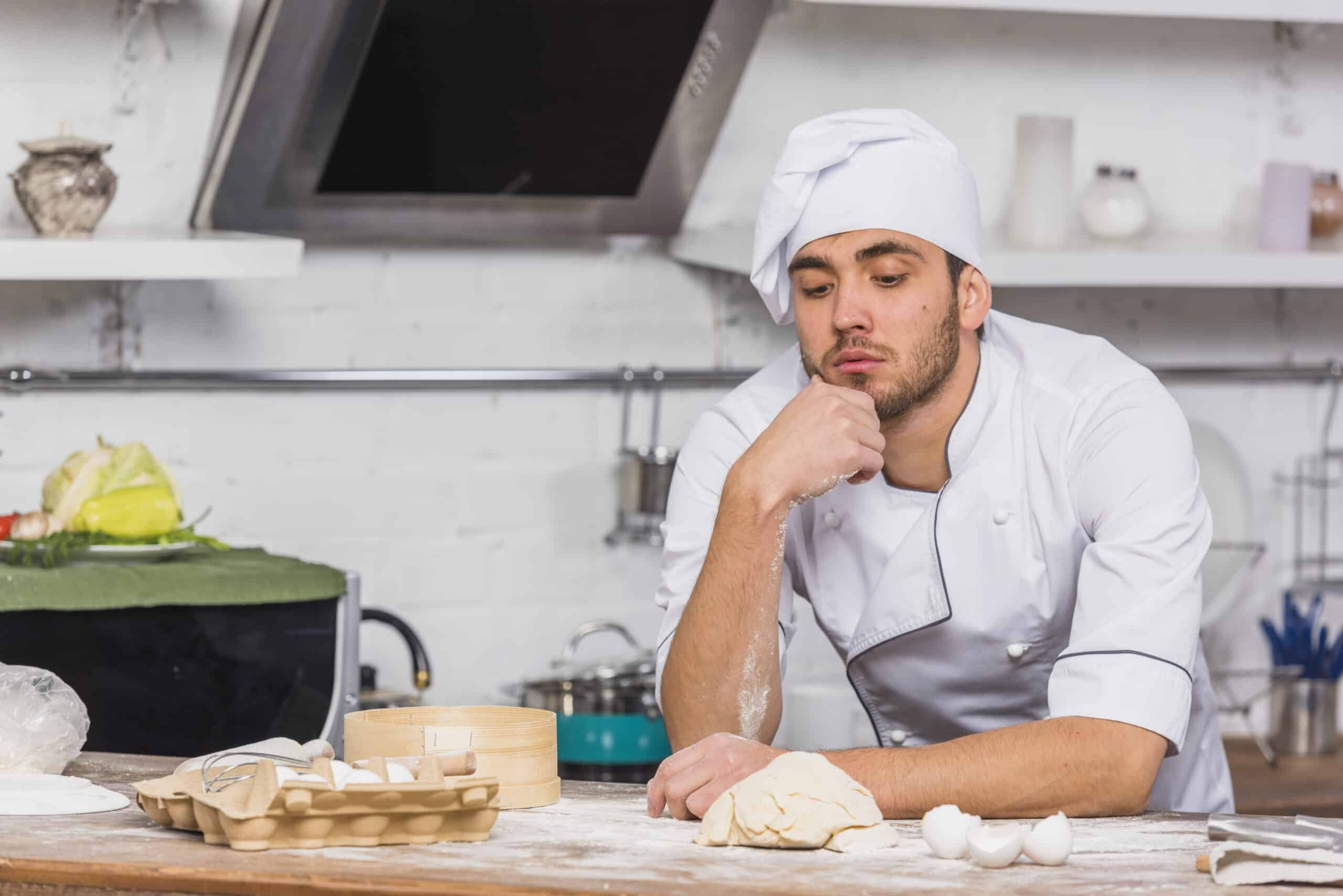 Chef kneading dough in a professional kitchen setting